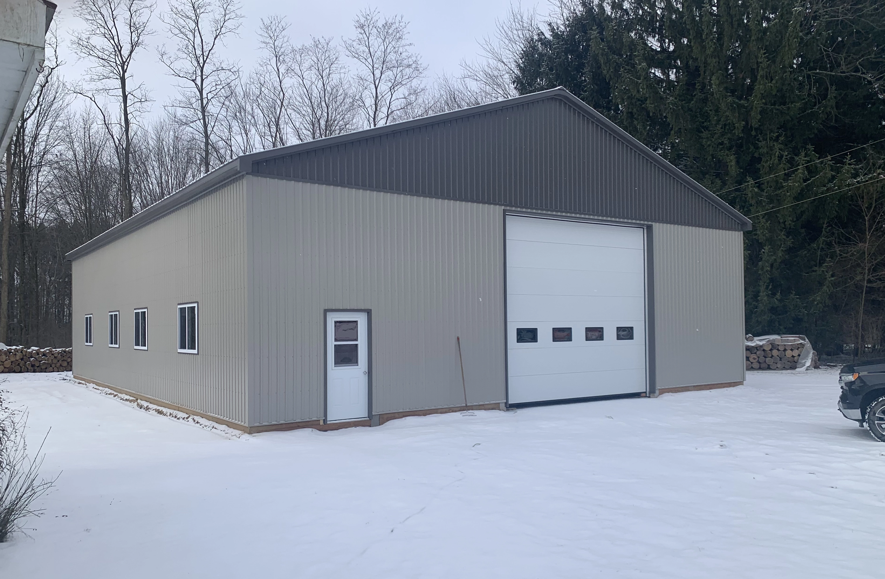 Grey steel garage with oversized overhead door in winter